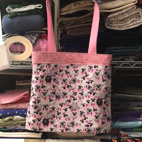 Reversible shopping tote, main fabric pink background, design is cartoon sheep
