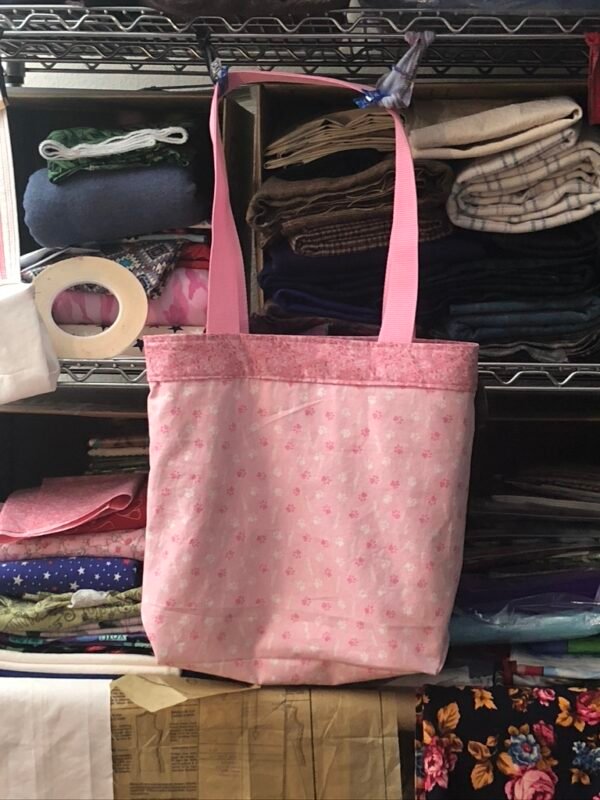 Reverse side of sheep fabric shopping tote. Main fabric medium pink print, top band darker pink.